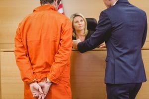 man in jail jumpsuit in a courtroom